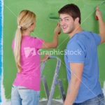 happy couple paint wall at new home