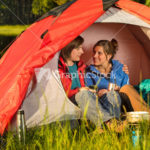 Camping teenagers sitting and embracing in tent