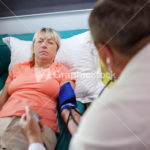 Doctor checking womans blood pressure