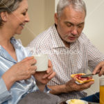 Elderly couple eating romantic breakfast in bed