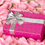 Gift box wrapped with the ribbon on rose petals