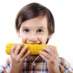 Little boy eating corn