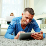 Man using a tablet computer while his girlfriend using laptop at home