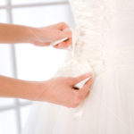 Bride putting white wedding dress
