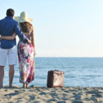 couple on beach with travel bag